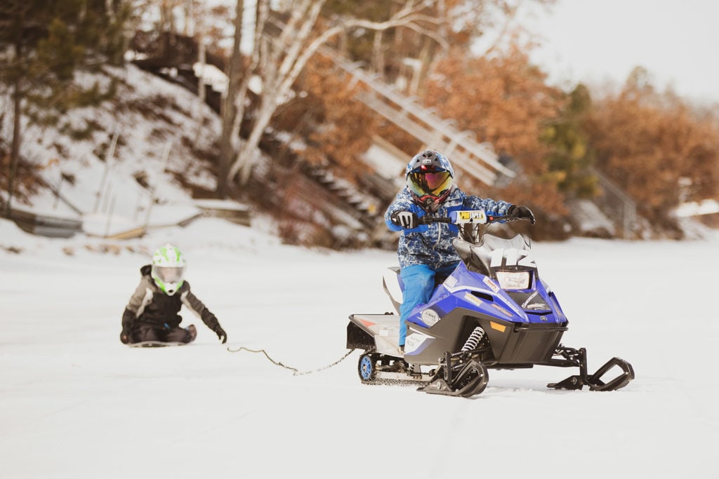 snowmobile pulling kid on sled