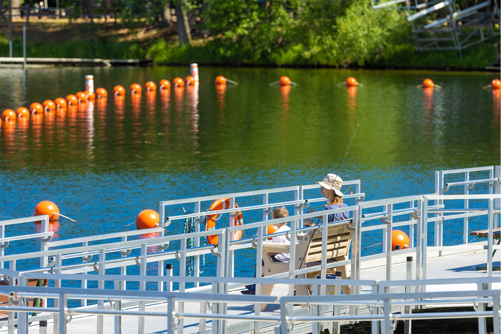 Two people sitting on a pier on a lake